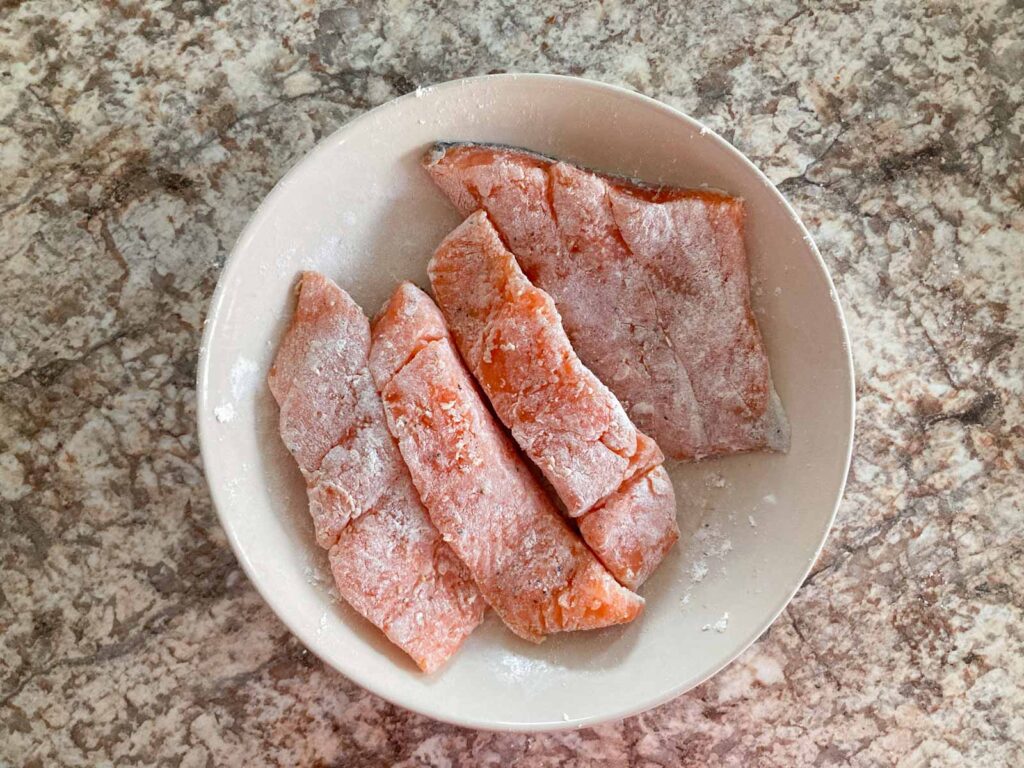 four slices of salmon coated with flour on a plate