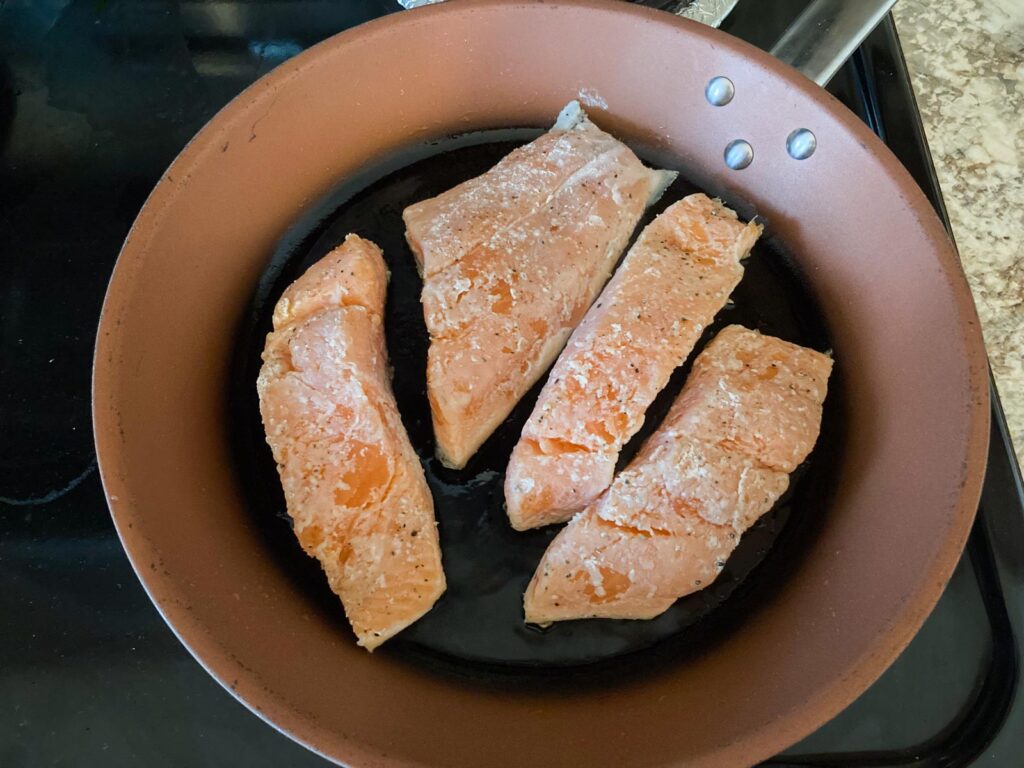 four slices of salmon on a frying pan