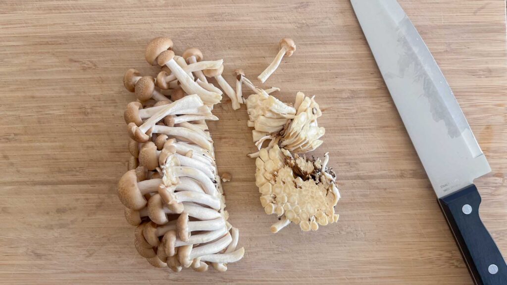 shimeji mushroom that the stem is cut on a cutting board.