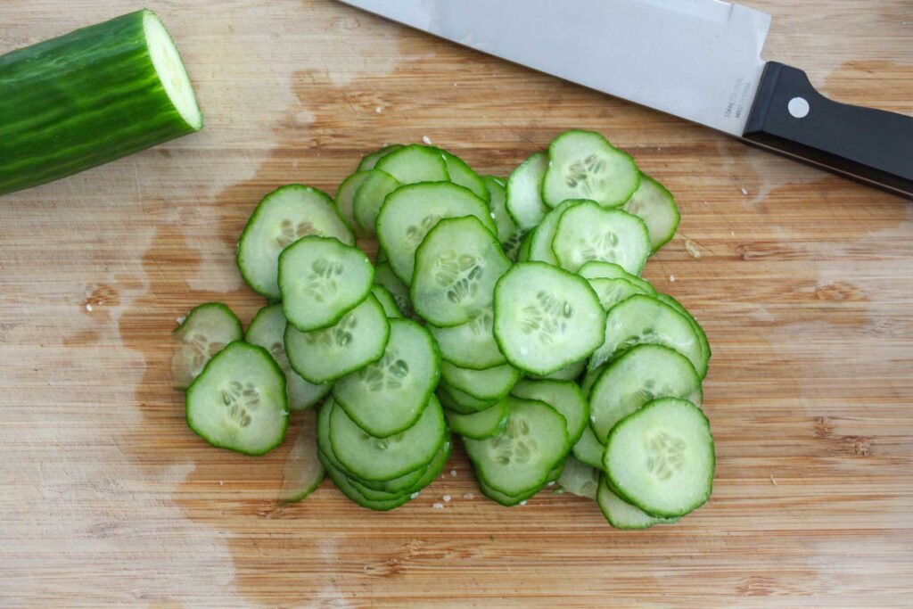 coined cucumbers on a cutting board, sprinkled salt.