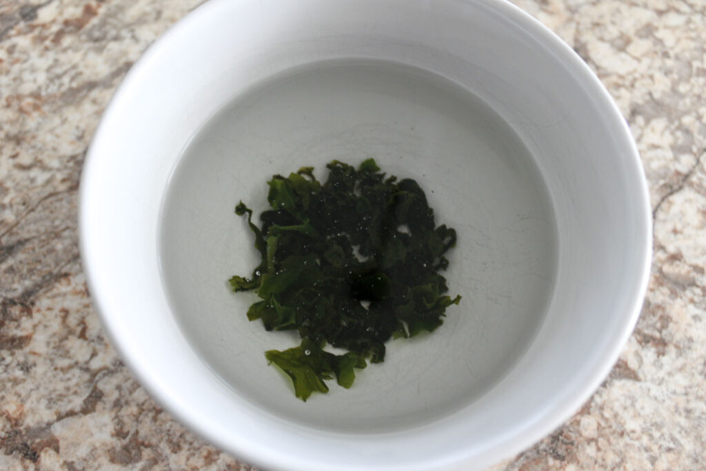 a bowl with cut dried wakame and water in it.