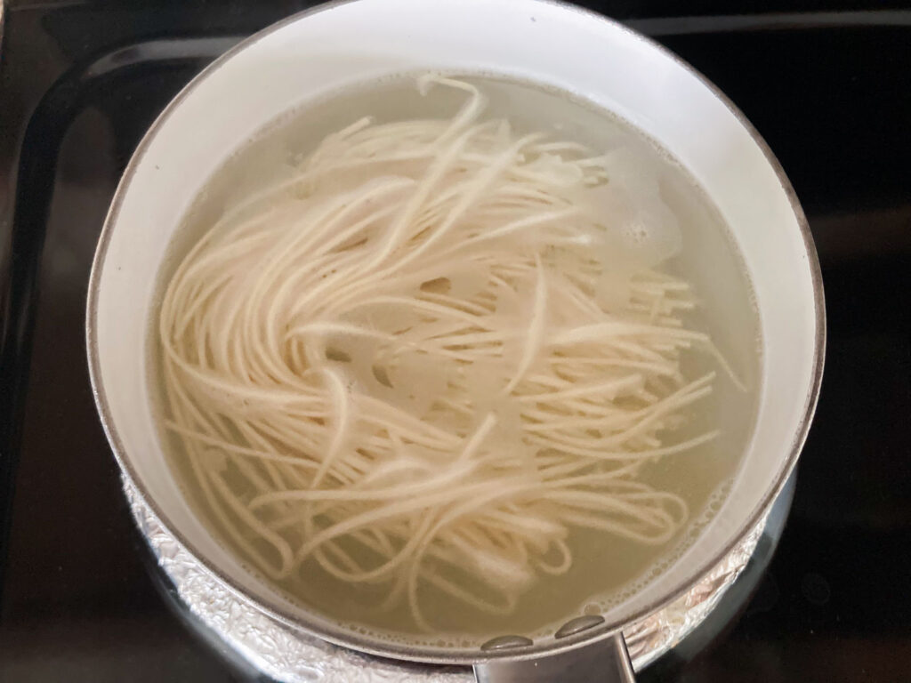 chinese noodles are boiled in a pot