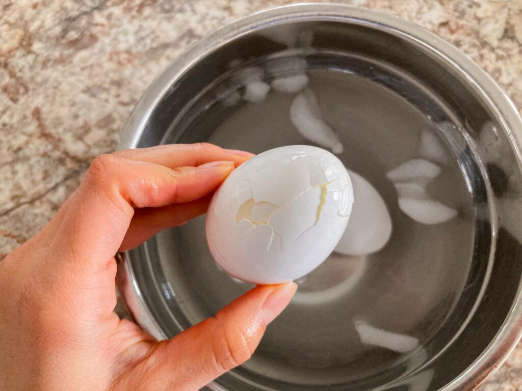 a hand is holding a boiled egg with cracks on the surface