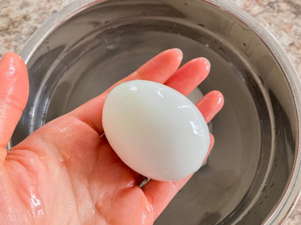 a hand is holding a boiled egg without the shell