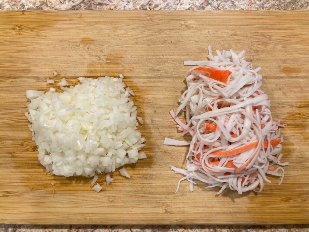 minced onions and shredded imitation crab on a cutting board