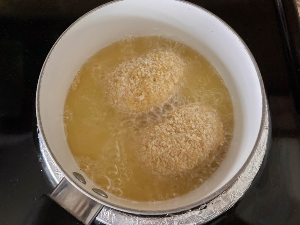 two creamy crab croquettes are deep-fried in a pot