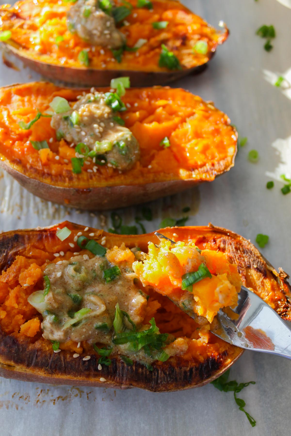 three half roasted potatoes topped with miso butter, scallions, and white sesame