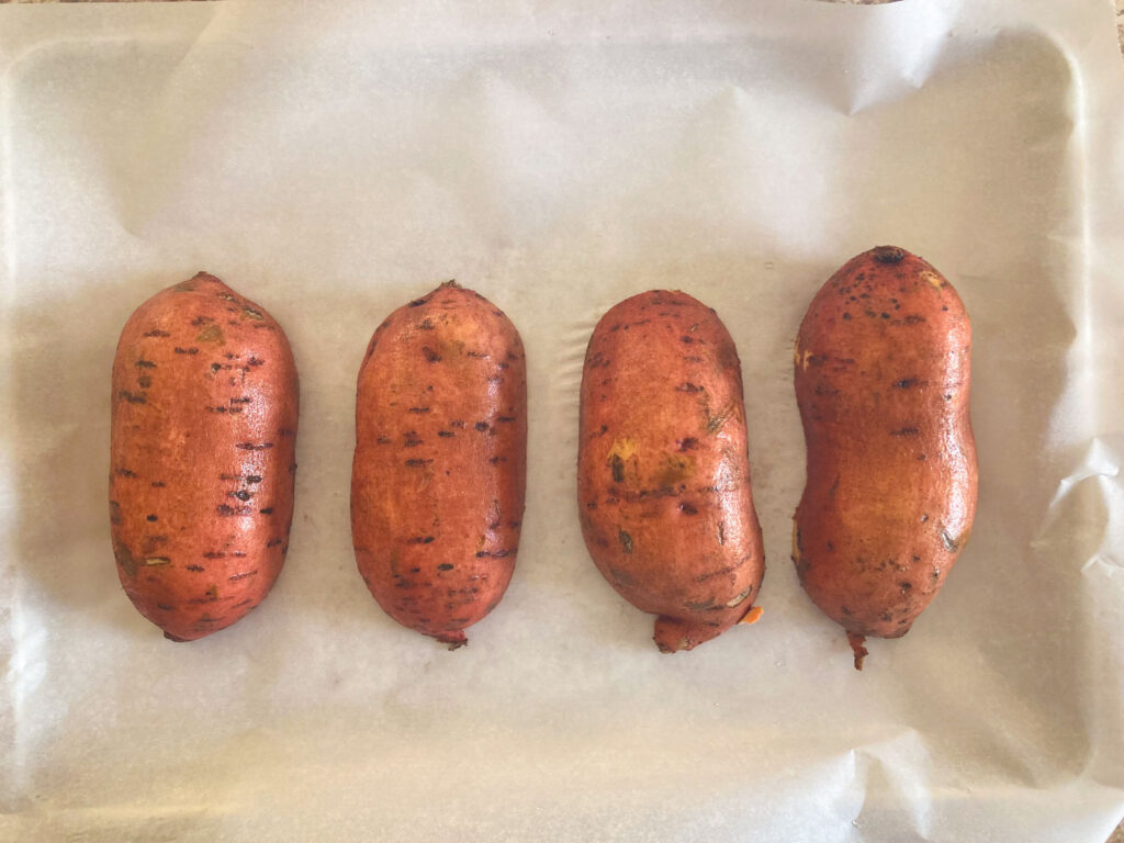 Arrange four lengthwise-cut sweet potato halves, cut side down, on a sheet of parchment paper