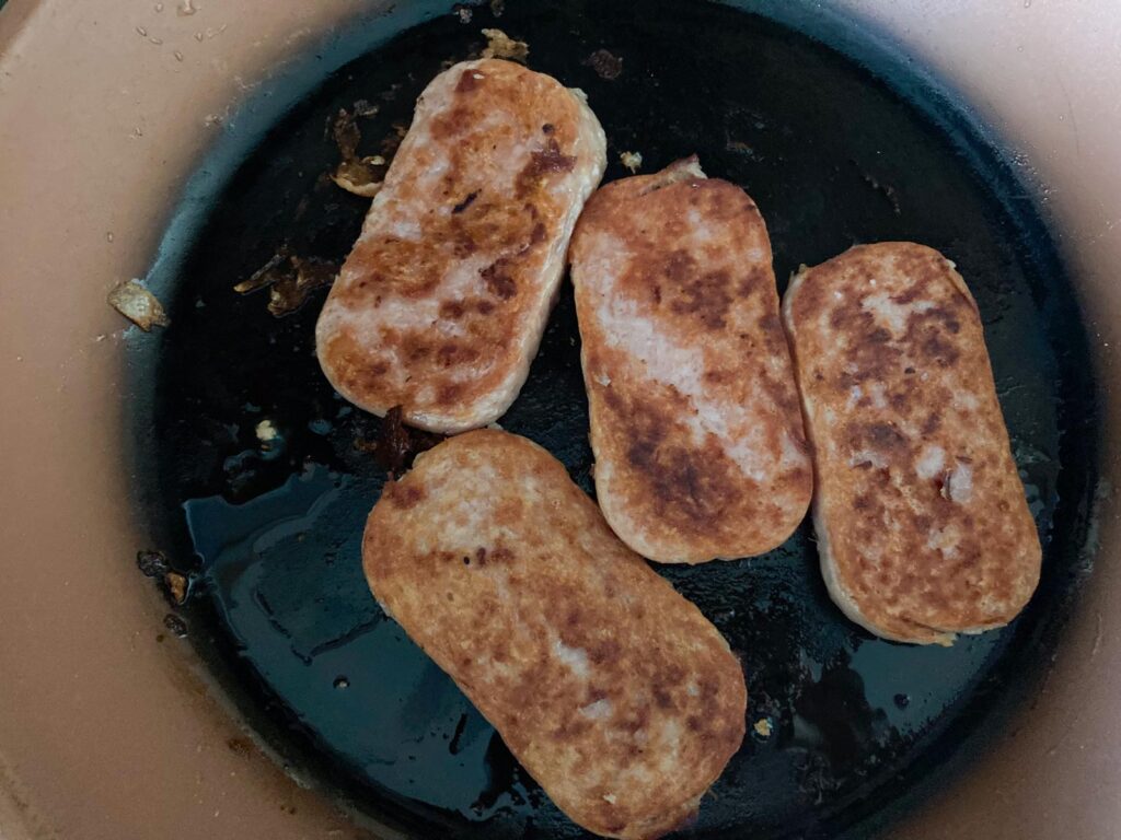 four slices of spam is fried in a pan