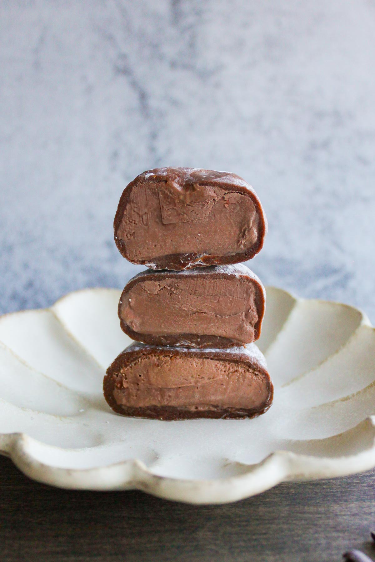 three half of chocolate mochi ice cream stacked on a plate