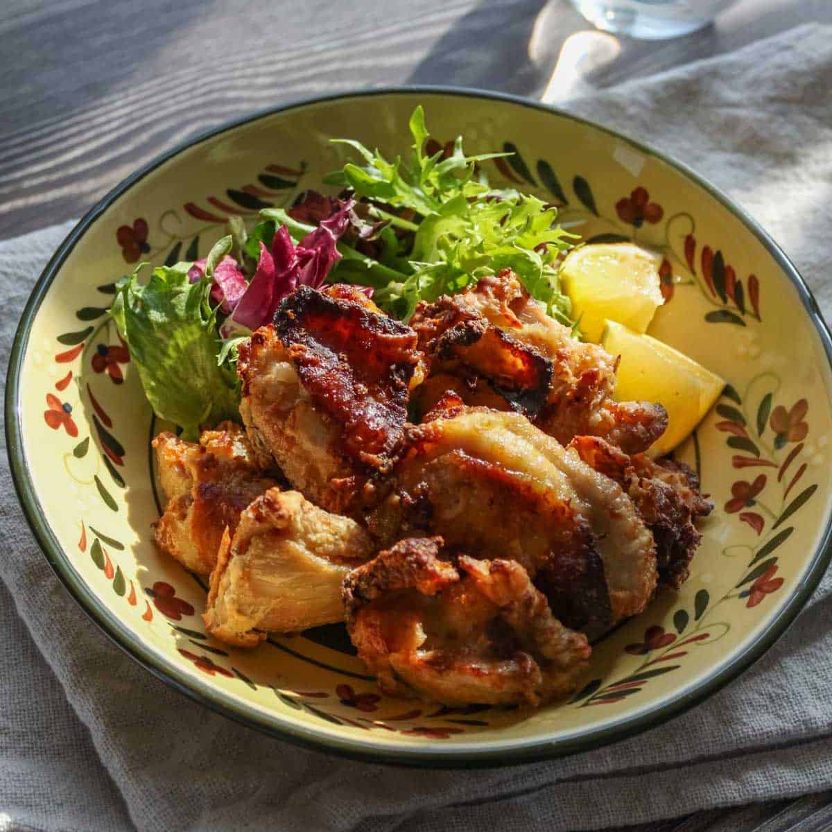 karaage are plated with green mix and lemon wedges.
