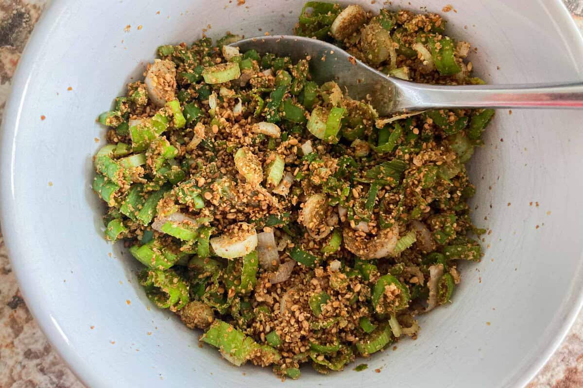 minced scallions and ground white sesame seeds mixed in a bowl.