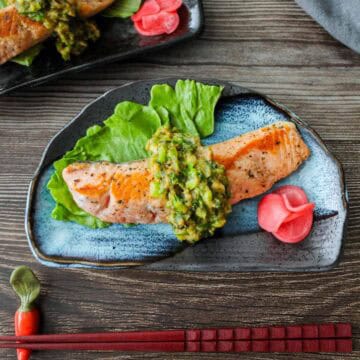 salmon topped with miso butter scallion sauce on a plate.