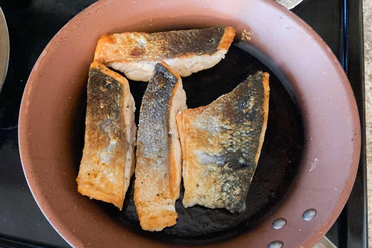 sliced of salmon are cooked on a pan.