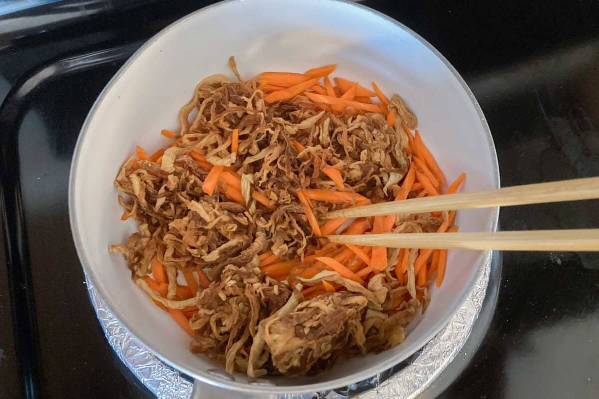 kiriboshi daikon and carrots are sauteed in a pot.