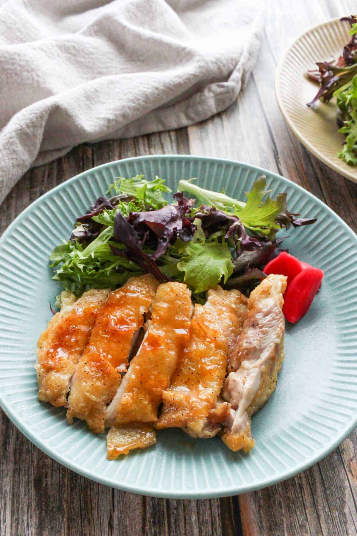 Teriyaki chicken and green mix salad on a plate.