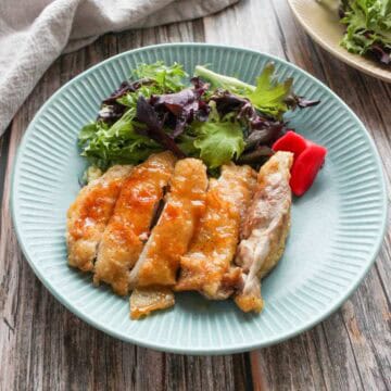 Teriyaki chicken and green mix salad on a plate.