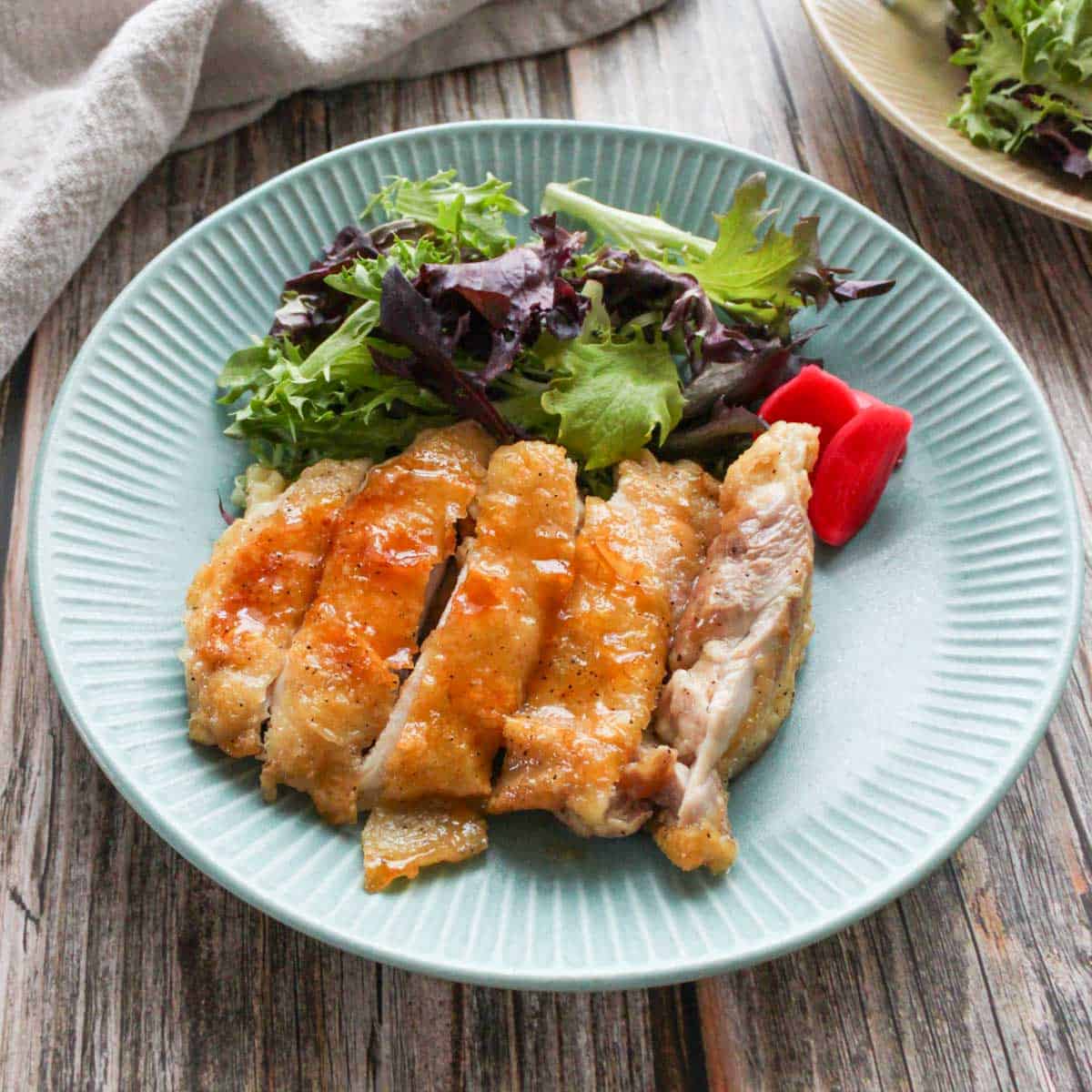 Teriyaki chicken and green mix salad on a plate.