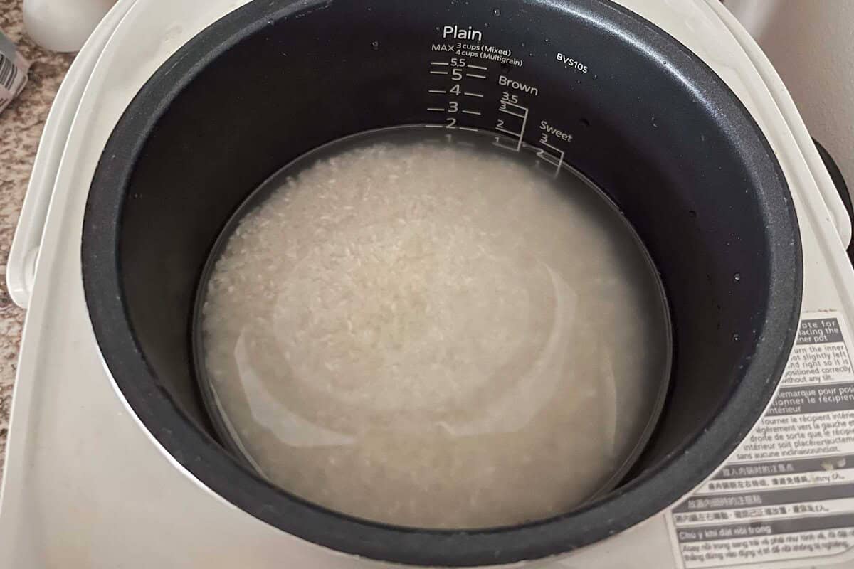 Rice is soaked in water in a rice cooker.