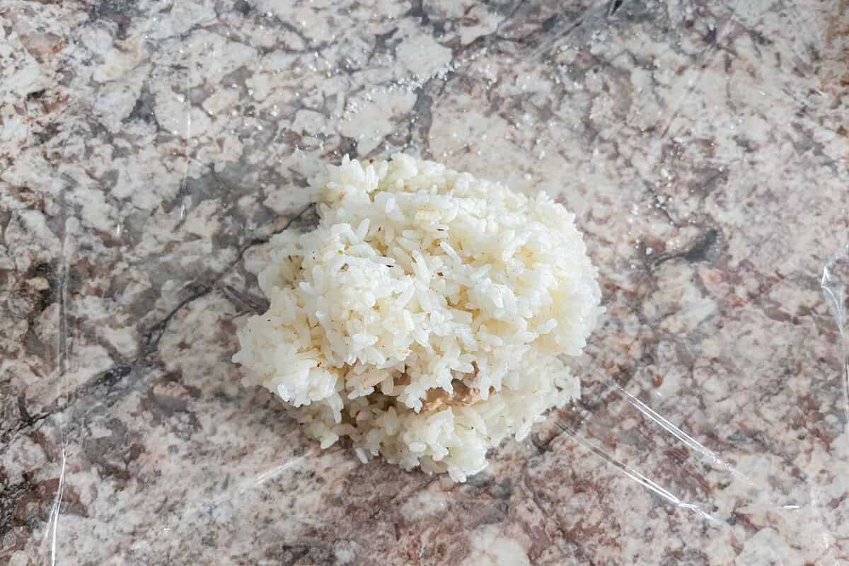 Rice and tuna mayo mixture on a plastic wrap.