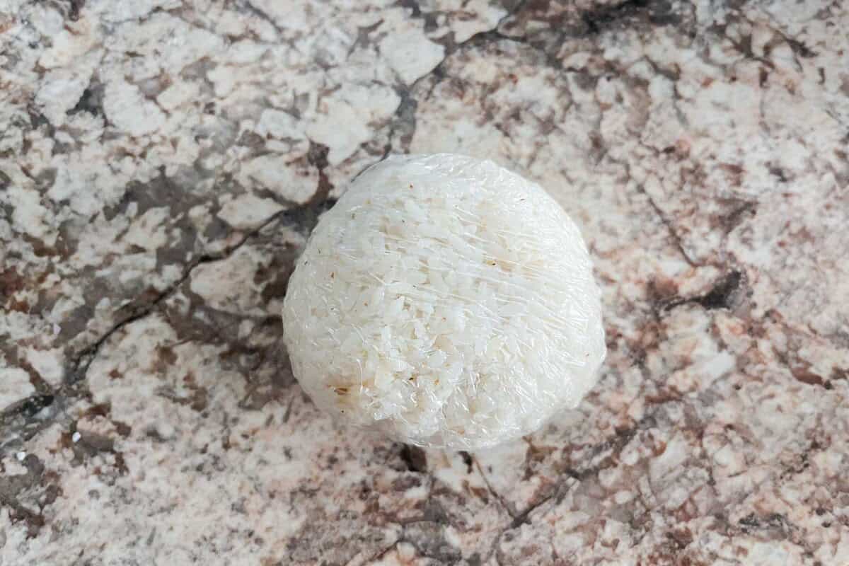 A rice ball wrapped with a plastic wrap.