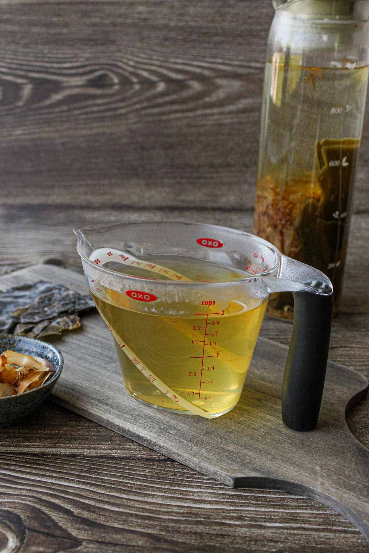 Awase dashi in a measuring cup, bonito flakes and kombu on the side.