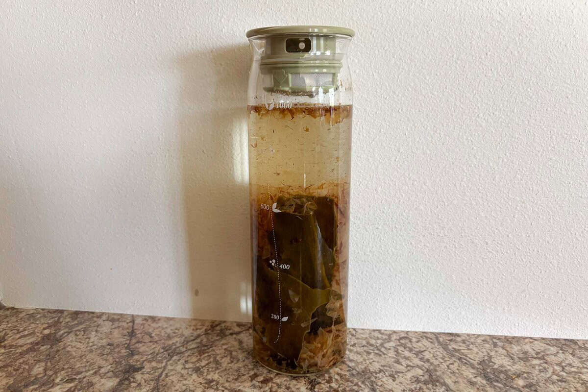 kombu and bonito flakes are soaked in water in a glass bottle.