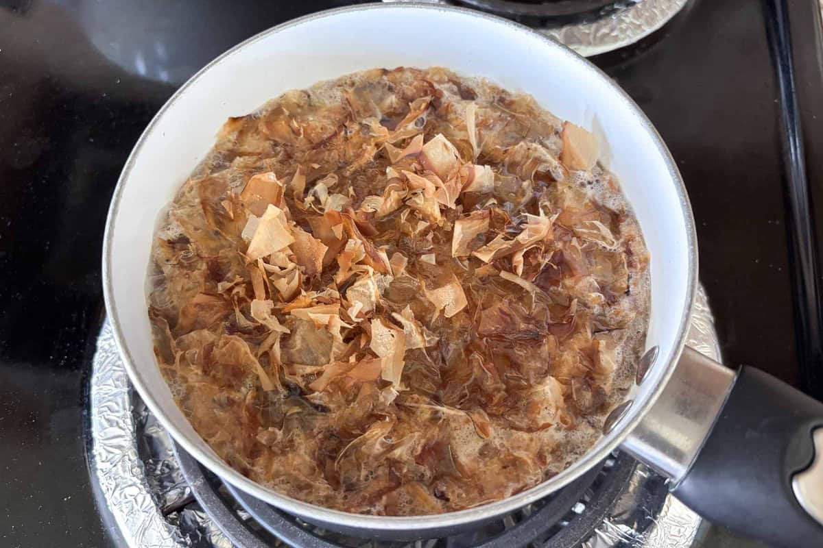 bonito flakes added to kombu dashi in a pot.