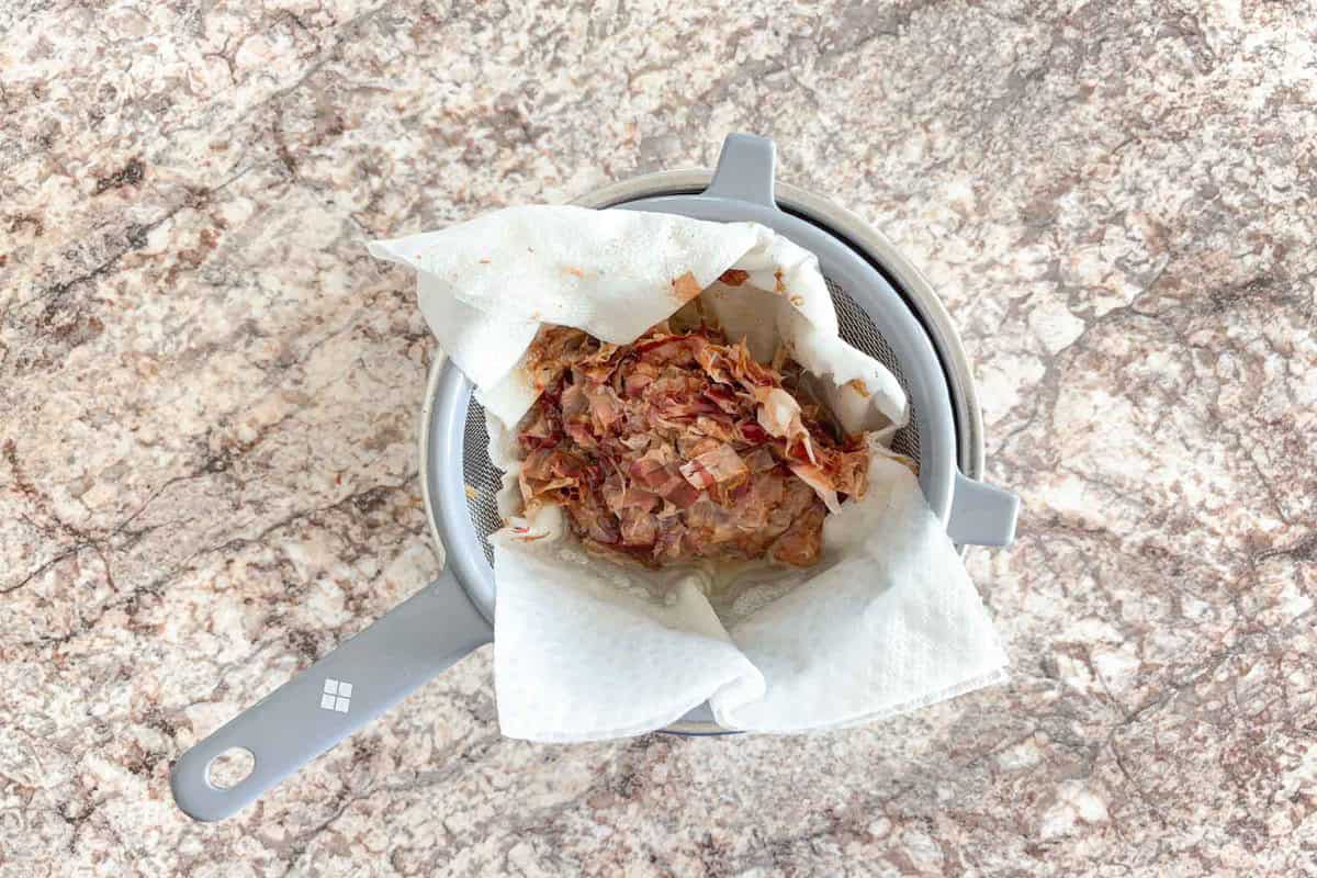 Strain katsuobushi through colander and a paper towel.