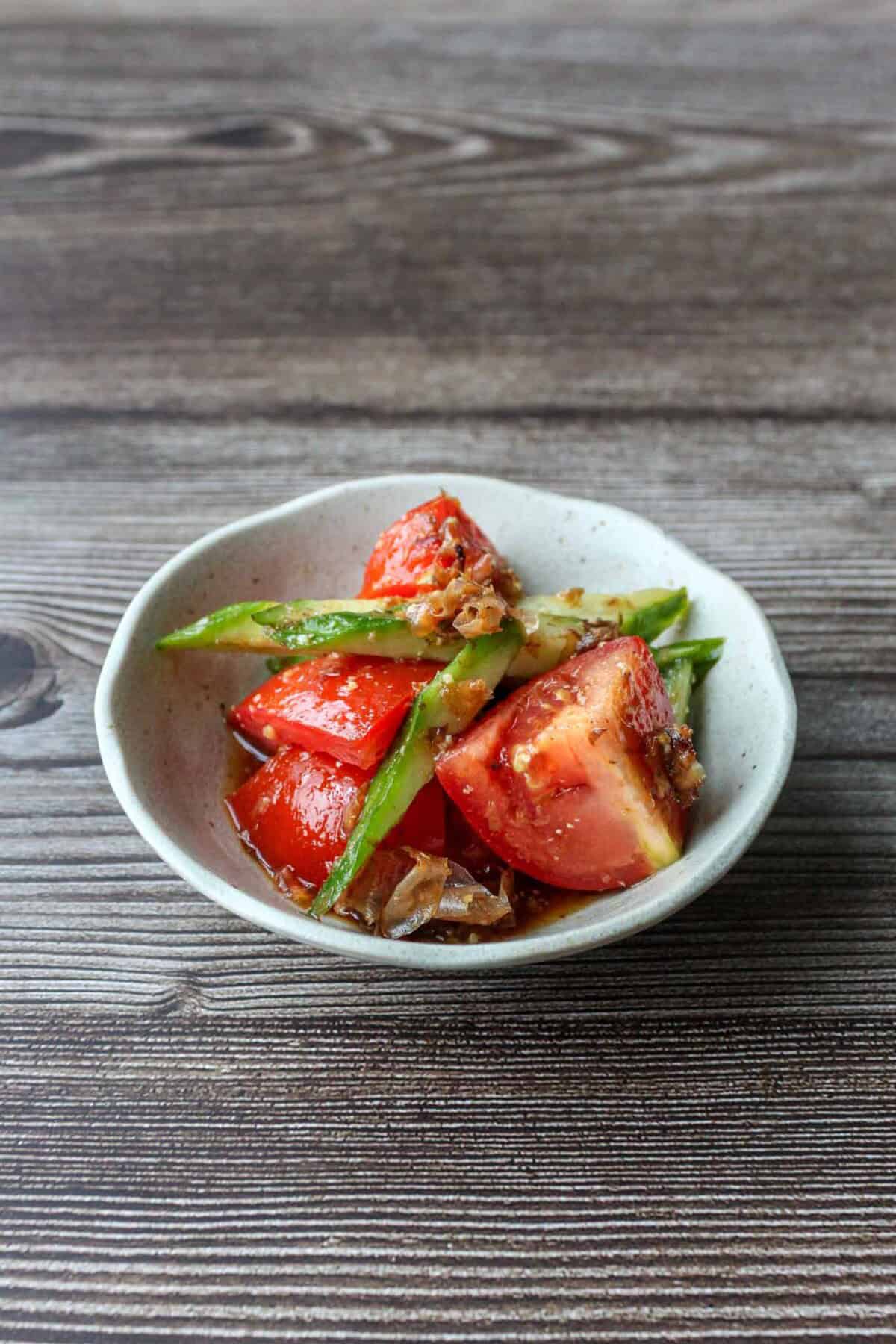 Japanese tomato salad with cucumbers and bonito flakes on a plate.