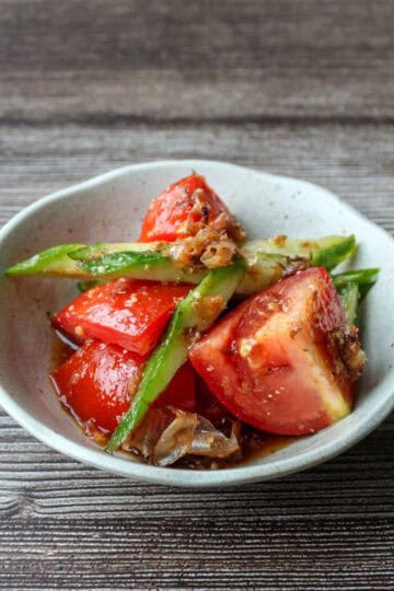 Japanese tomato salad with cucumbers and bonito flakes on a plate.