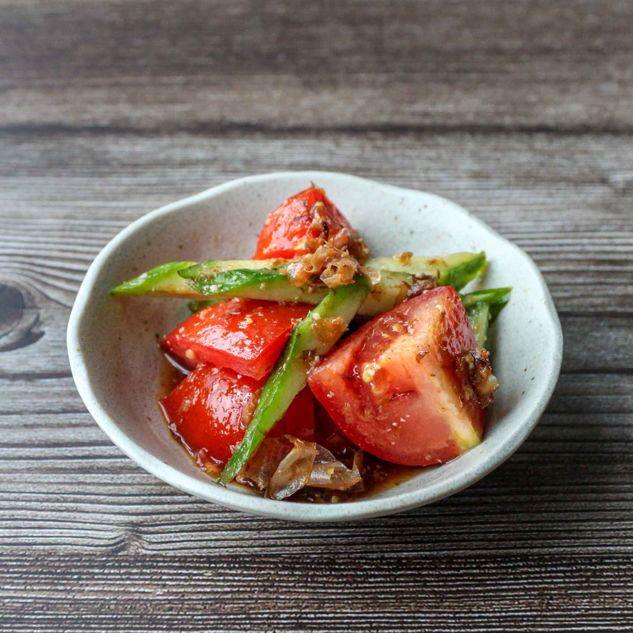 Japanese tomato salad with cucumbers and bonito flakes on a plate.
