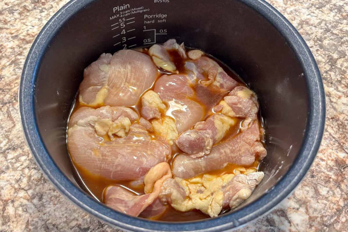Add chicken thighs to the rice cooker bowl.