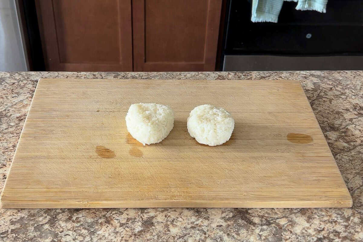 Two onigiri on a cutting board.