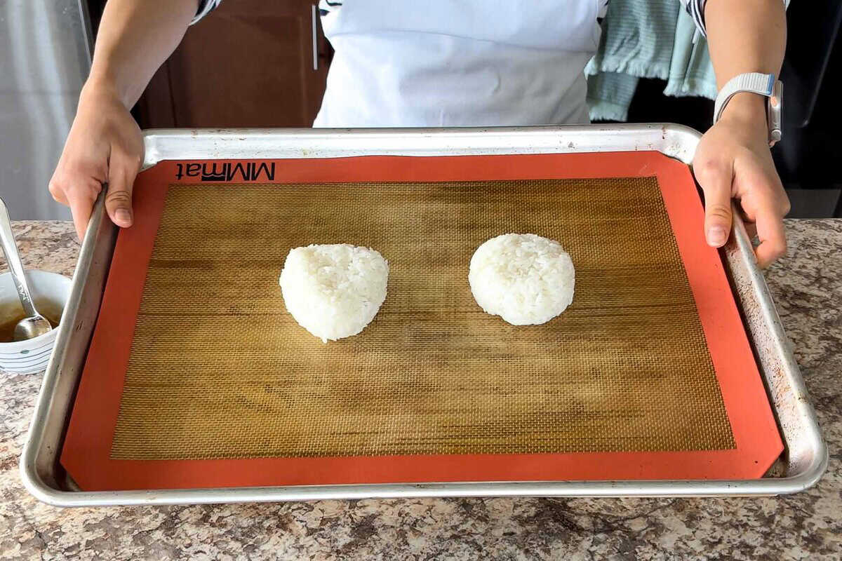 Two onigiri on a baking sheet.