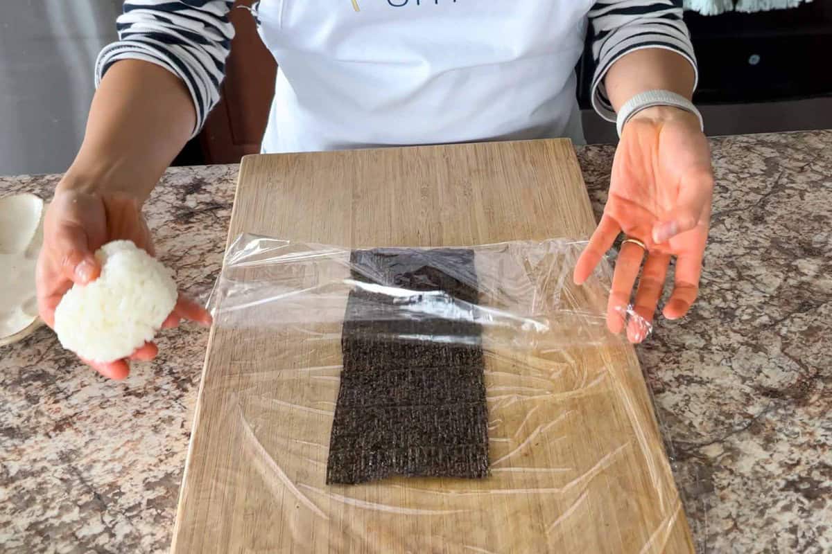 Fold the bottom of the plastic wrap over the nori.