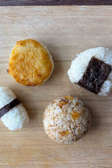Four onigiri on a cutting board.