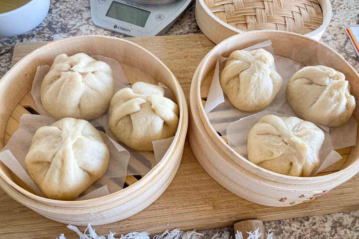 Three nikuman (Japanese steamed pork buns) in a steamer.
